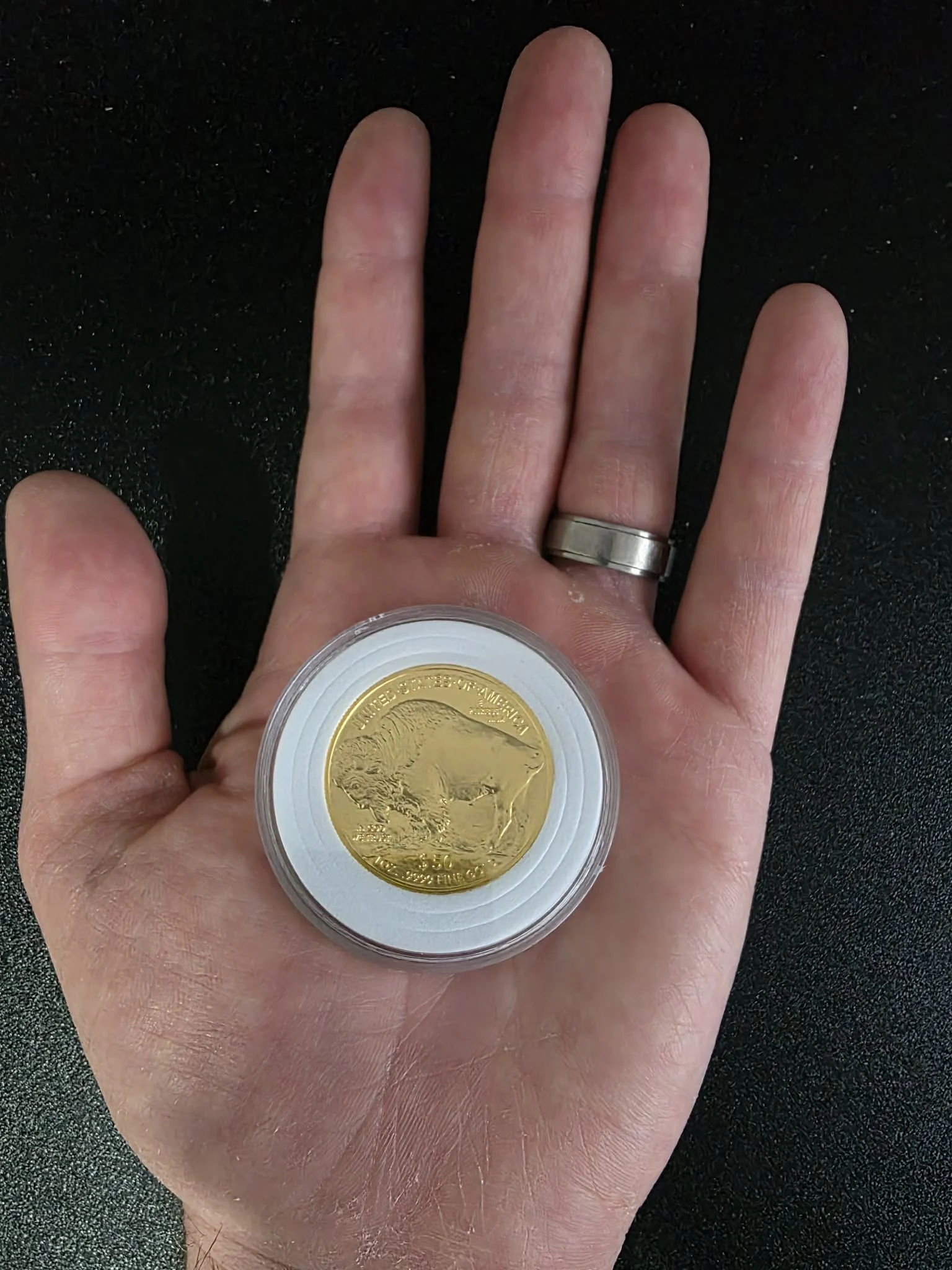 A one-ounce American Buffalo gold coin resting in a hand